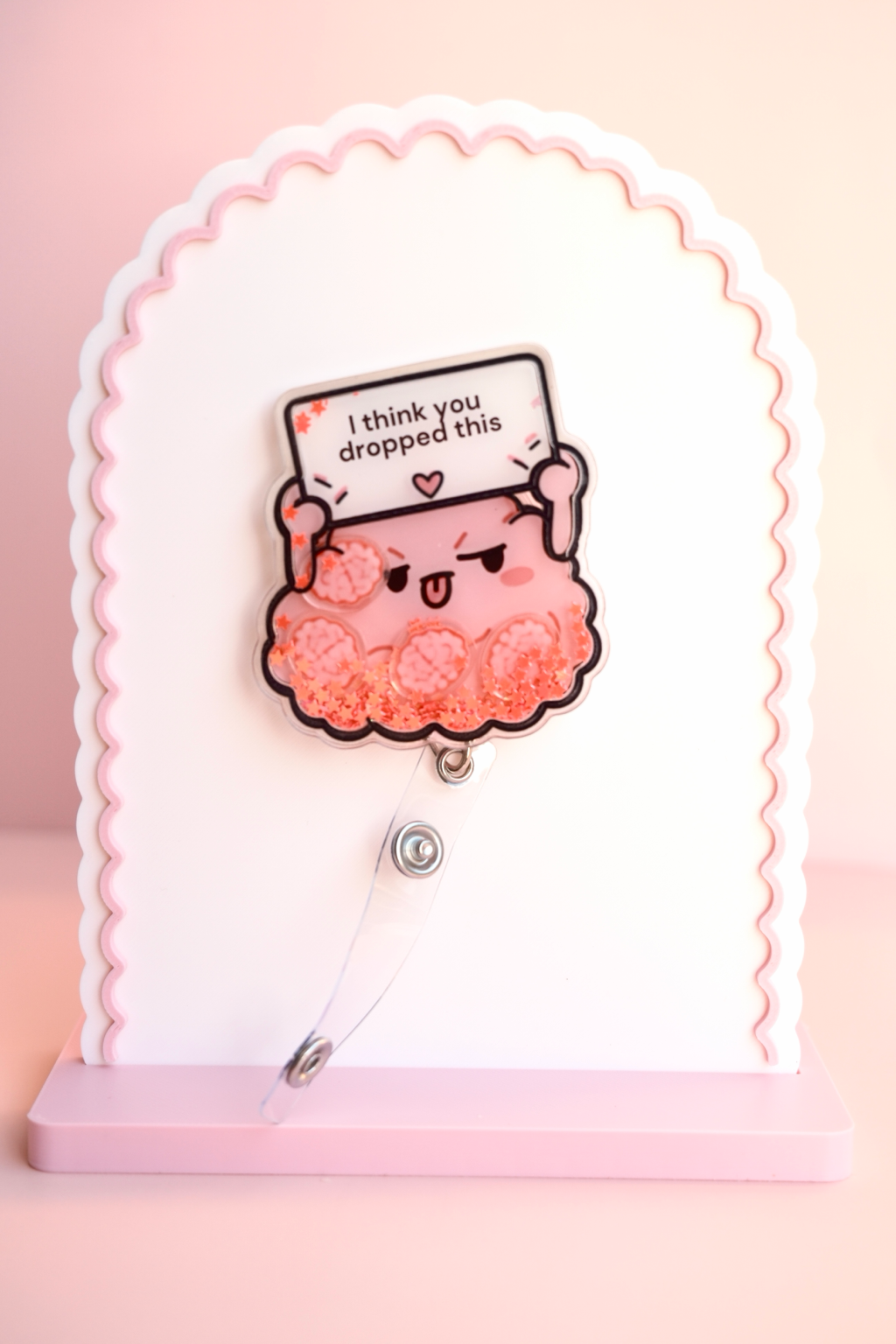 Pink brain badge shaker displayed with clear badge strap